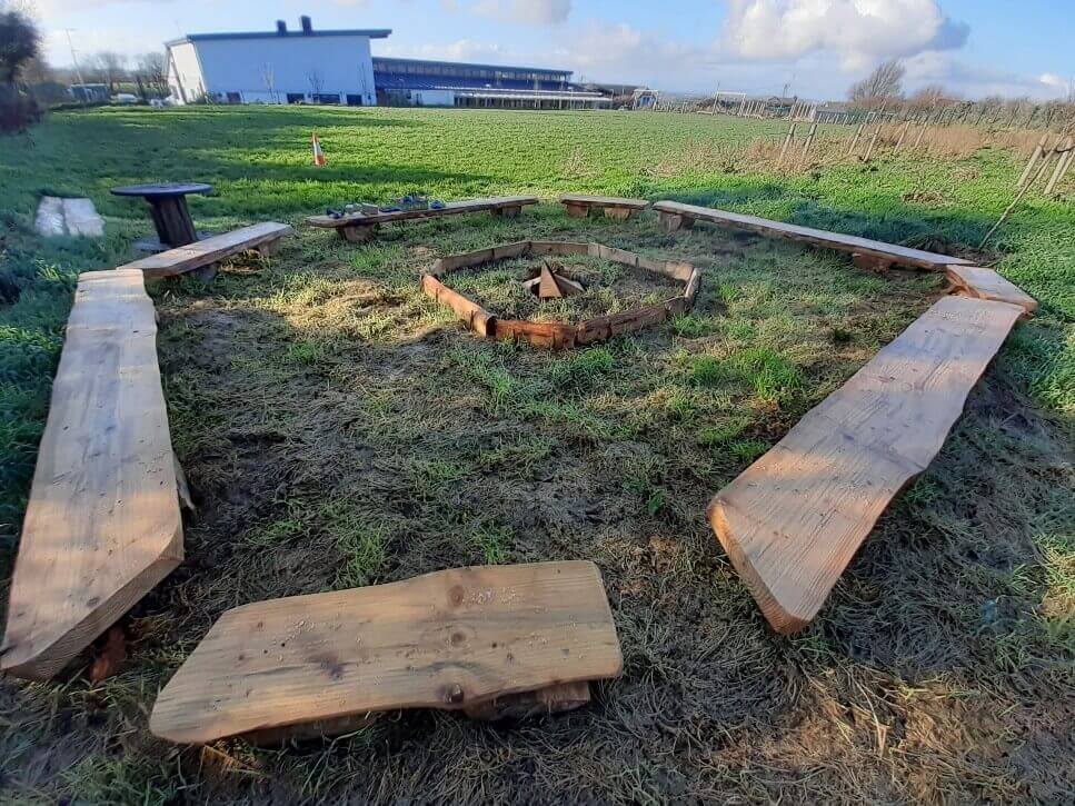 Tân gwersyll gyda boncyffion o'i gwmpas yn ffurfio cylch